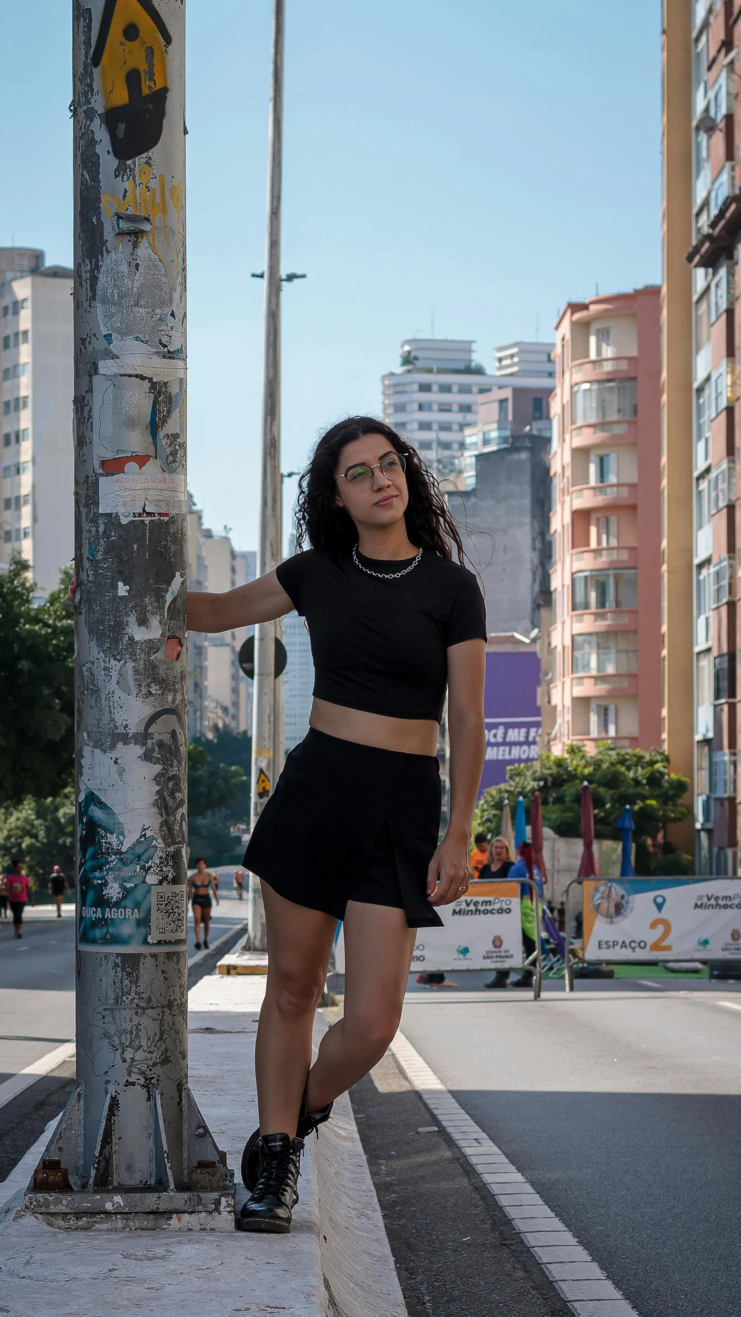 young woman in the city leaning on a pole