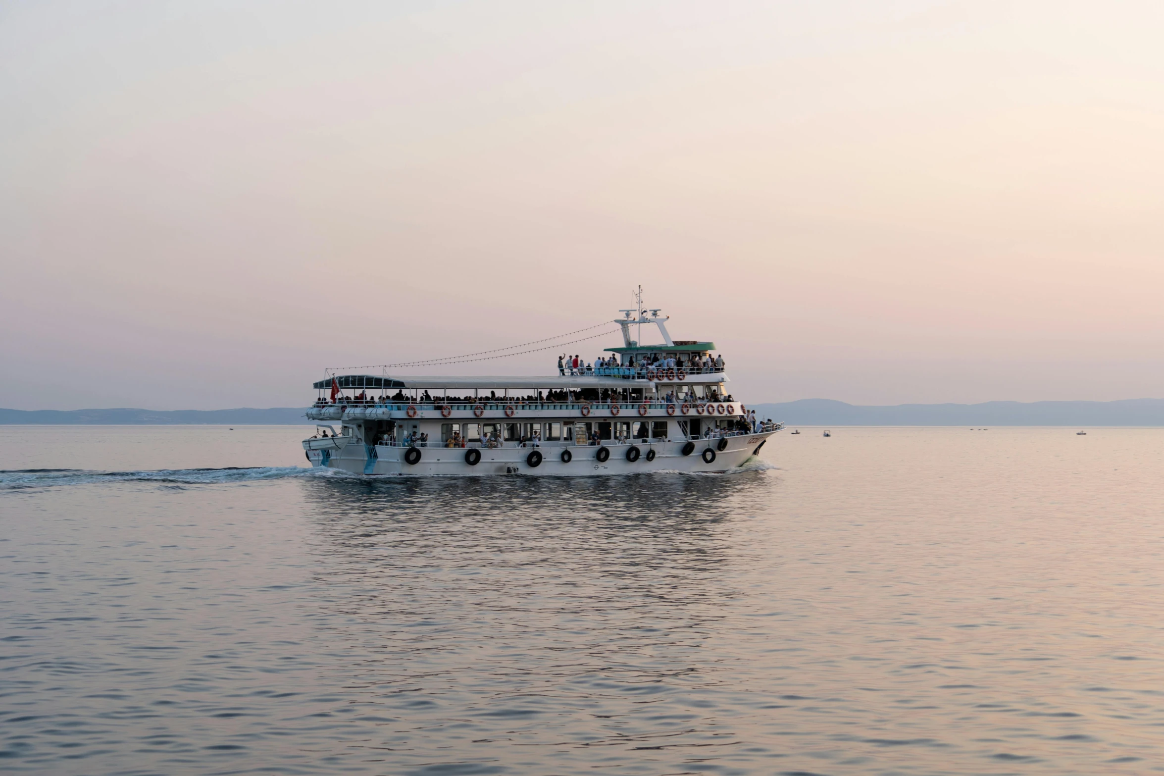 a passenger boat floating in the water during sunset