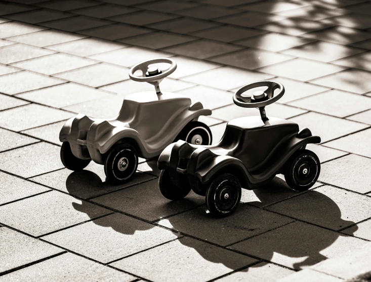 two children's pedal cars on an outdoor tiles background