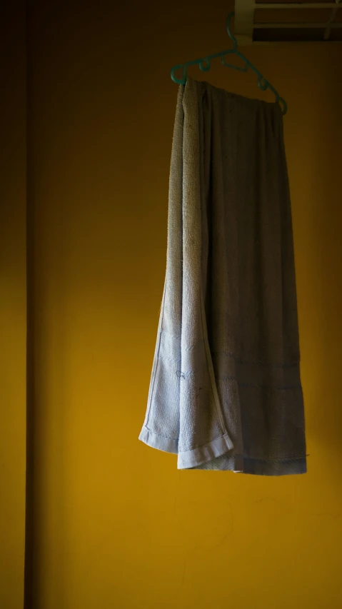 a towel hanging up against a yellow wall