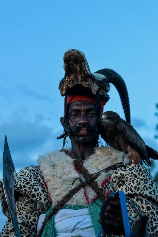 a man dressed in a lion headdress with his parrot perched on the shoulder