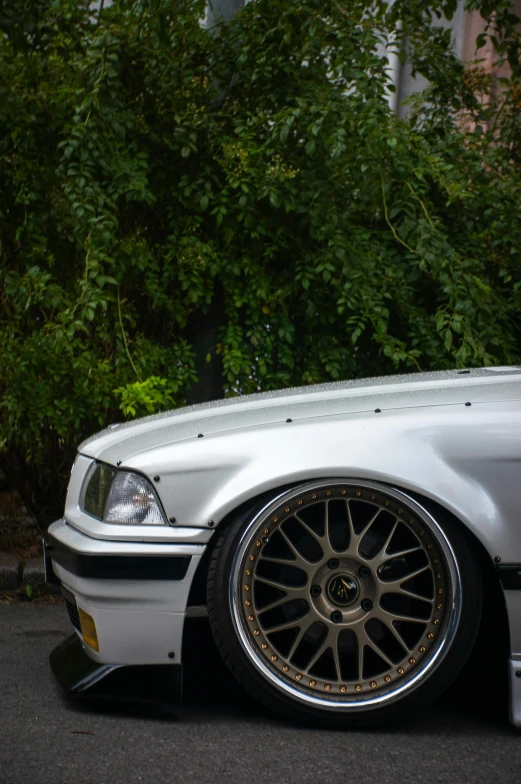 a white car with some gold rims parked on the street