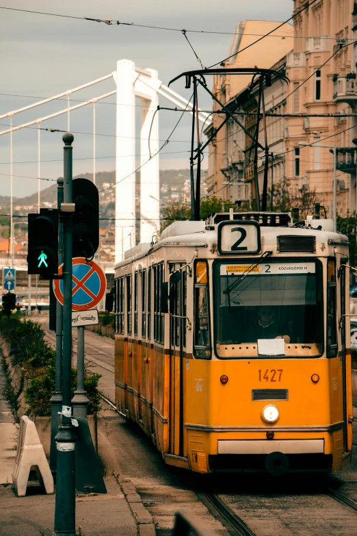 a yellow tram driving down the street in front of a traffic light