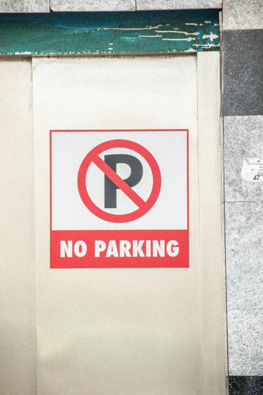 no parking sign painted on white wall next to grey and green panel