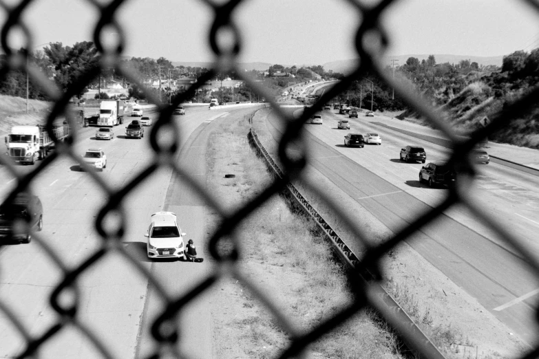 a po taken through the fence shows cars traveling on a highway