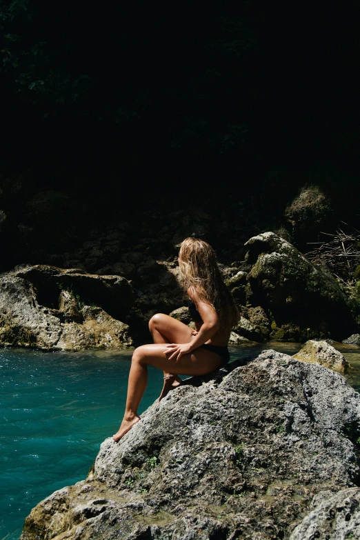 a girl sitting on a rock and looking at soing