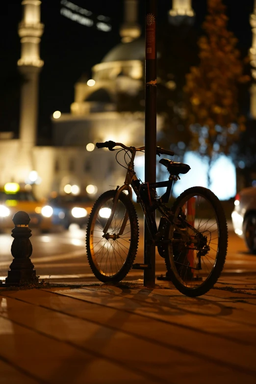bicycle parked next to a lamp post in the street at night