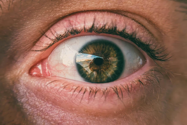 a closeup view of someones green eye and it's reflection