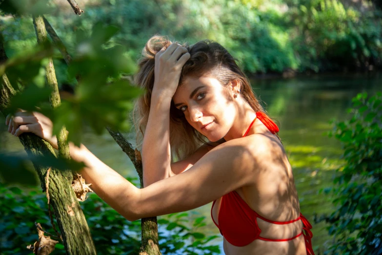 a woman in a bikini holding her head behind trees