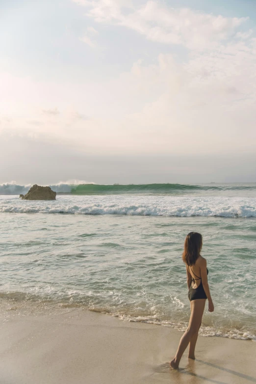 a girl walking along the beach next to an ocean