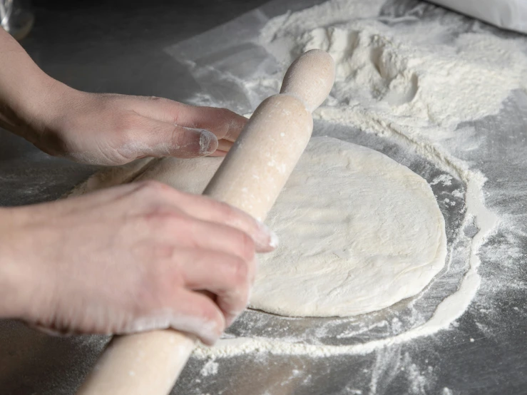 person preparing a doughnut in an apron and holding a rolling pin