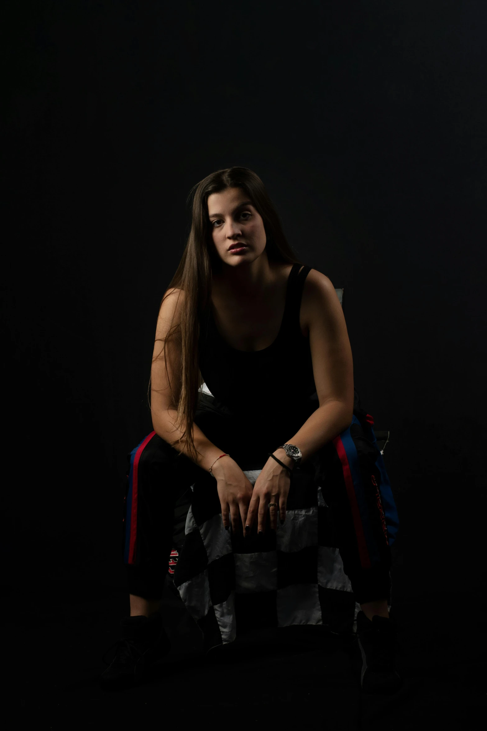 a woman in black top sitting on checkerboard purse