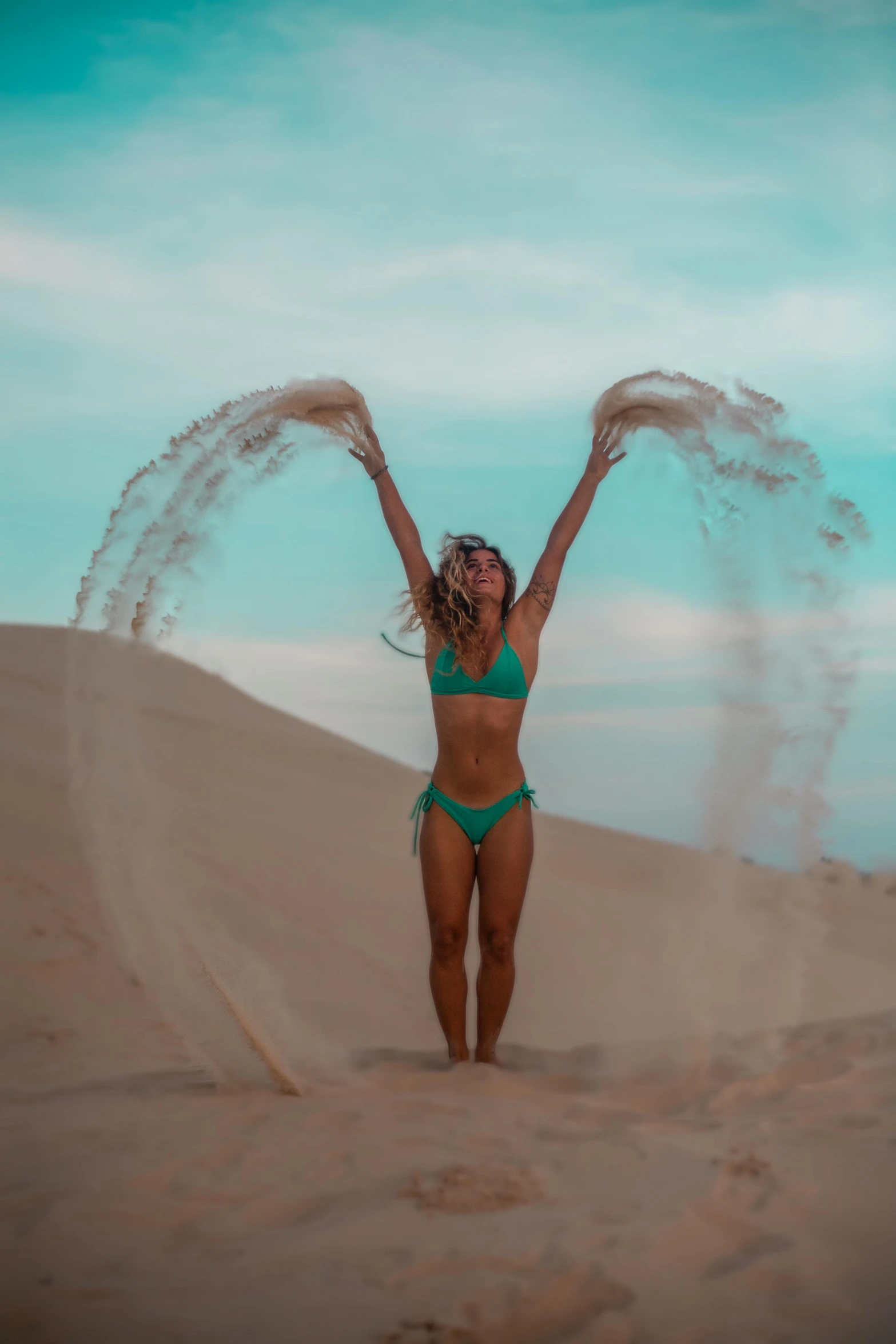 a woman in a bikini jumping off a dune