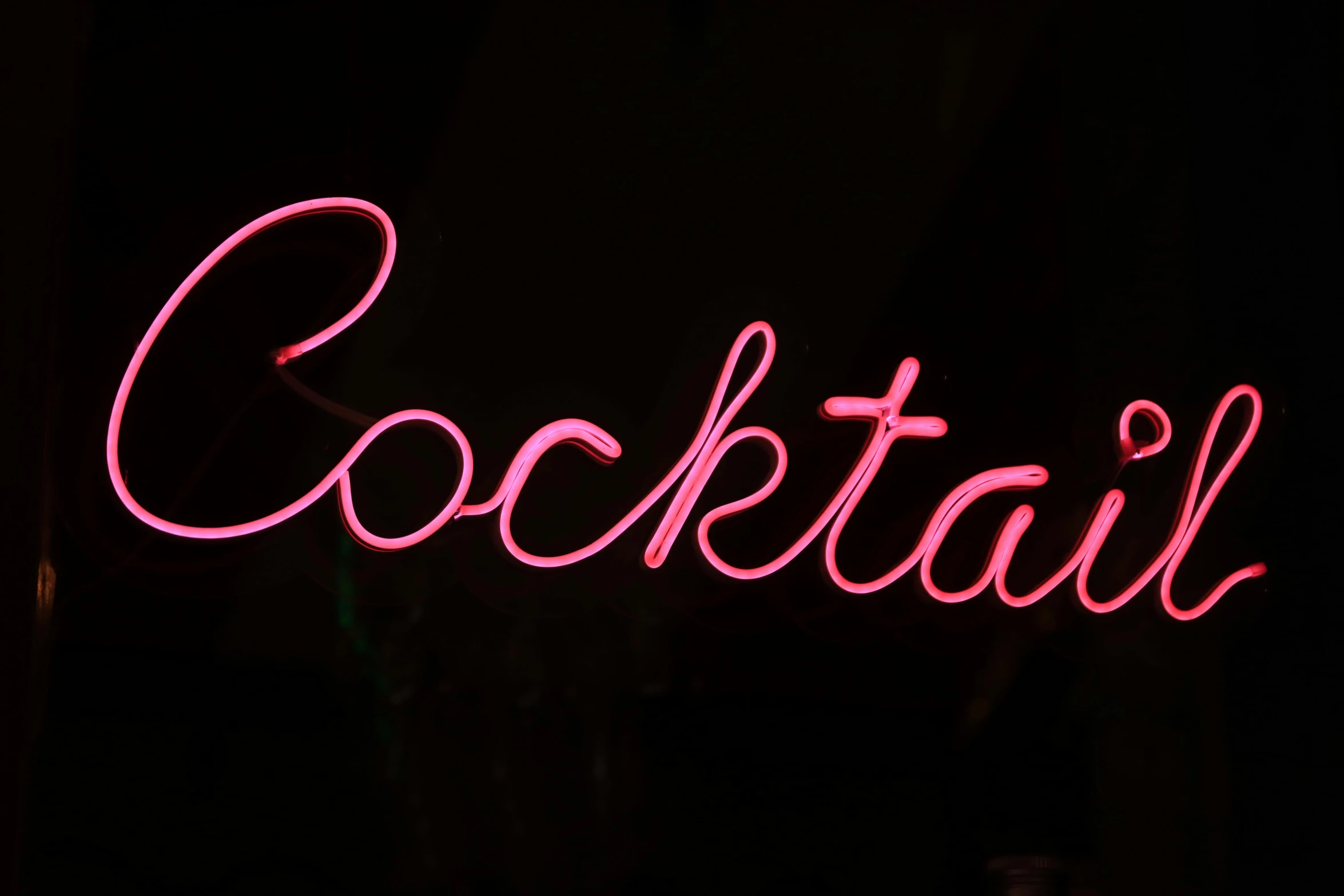 a red neon sign reading cocktail in front of a black background