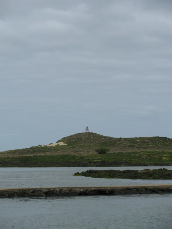 there is a lighthouse on a small hill over water