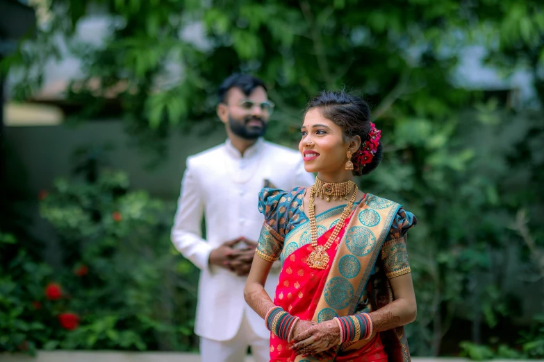 a couple in ethnic garb standing near some trees