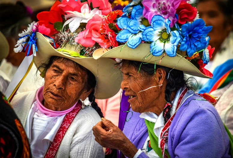 two women in native hats with flowers on their heads