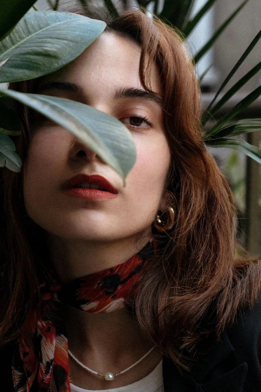 a woman with big earrings looks up while wearing a scarf