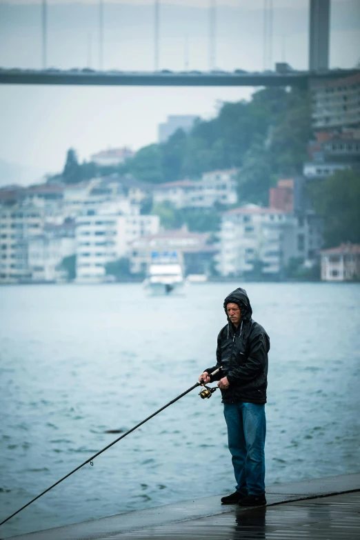 a man is fishing in a lake by some buildings