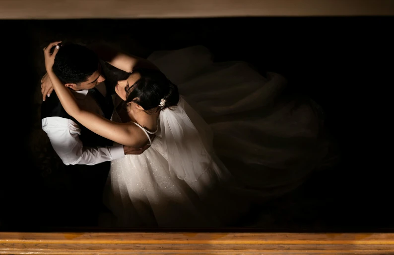 a bride and groom standing together in the dark