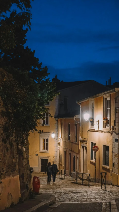 two people walk in a stone street at night