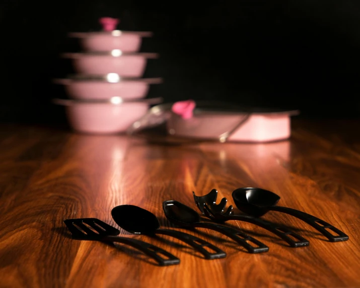 spoons and ladles on wooden table in front of stack of dishes