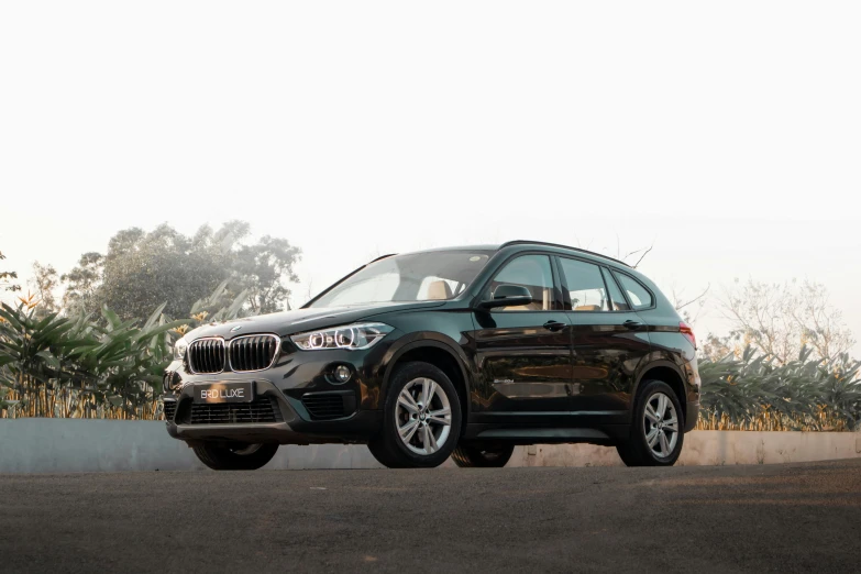 a close up of a bmw suv parked in front of some trees