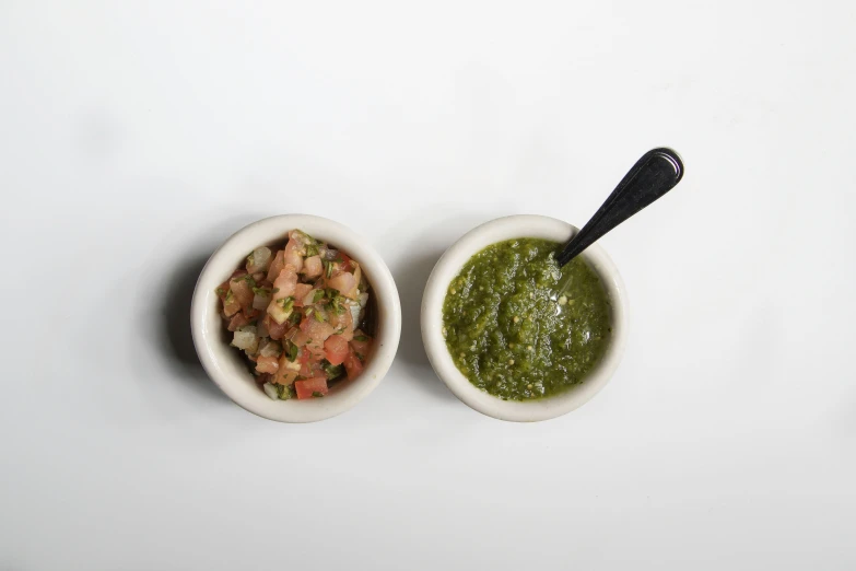 two small bowls of different vegetables, one has green, the other contains chopped meat