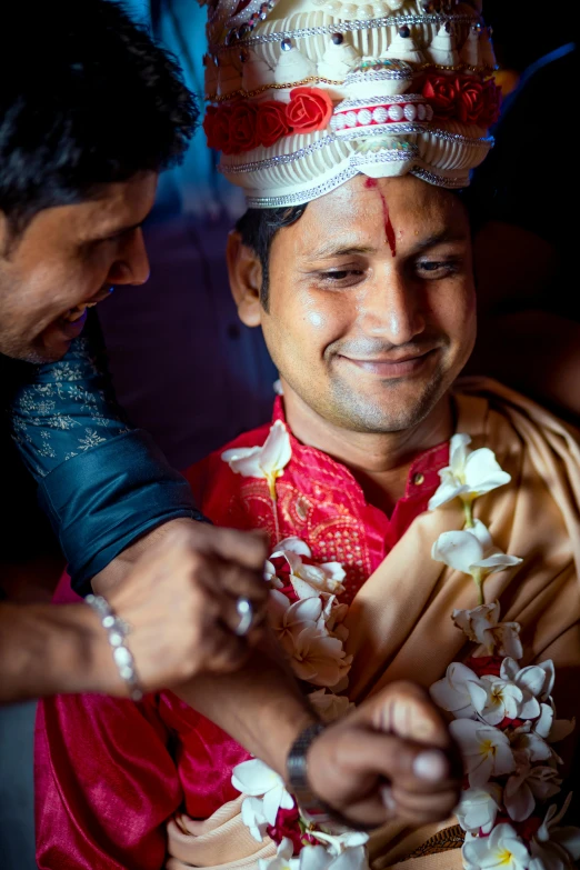 a man wearing a flowery headdress, while using his cell phone