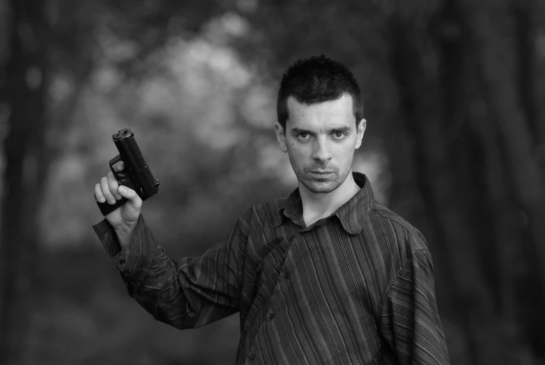 a young man holding up his cell phone in the woods