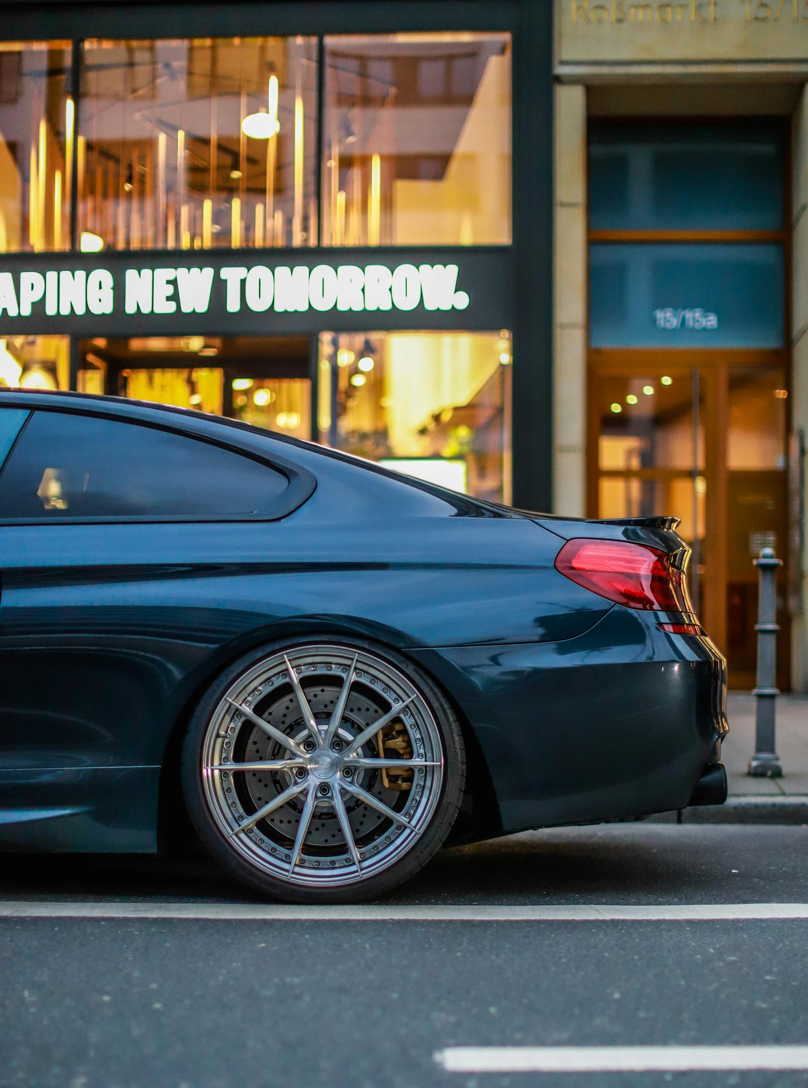 a black car sitting on the street next to a tall building