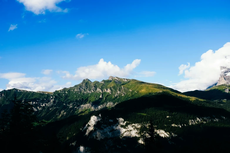 a clear blue sky and some clouds above the mountains