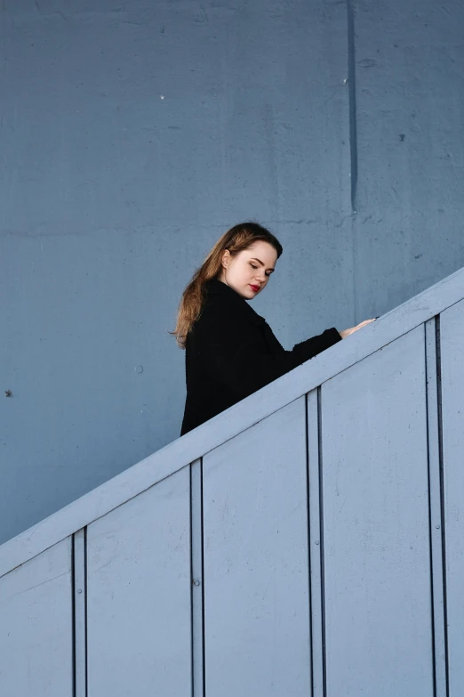 a young woman leaning against a blue wall