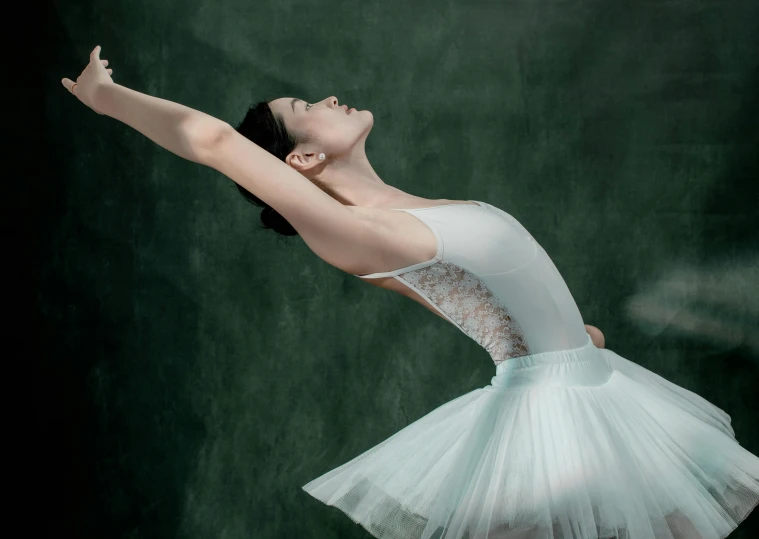 a young ballerina in a tutu and leotard, is looking upwards