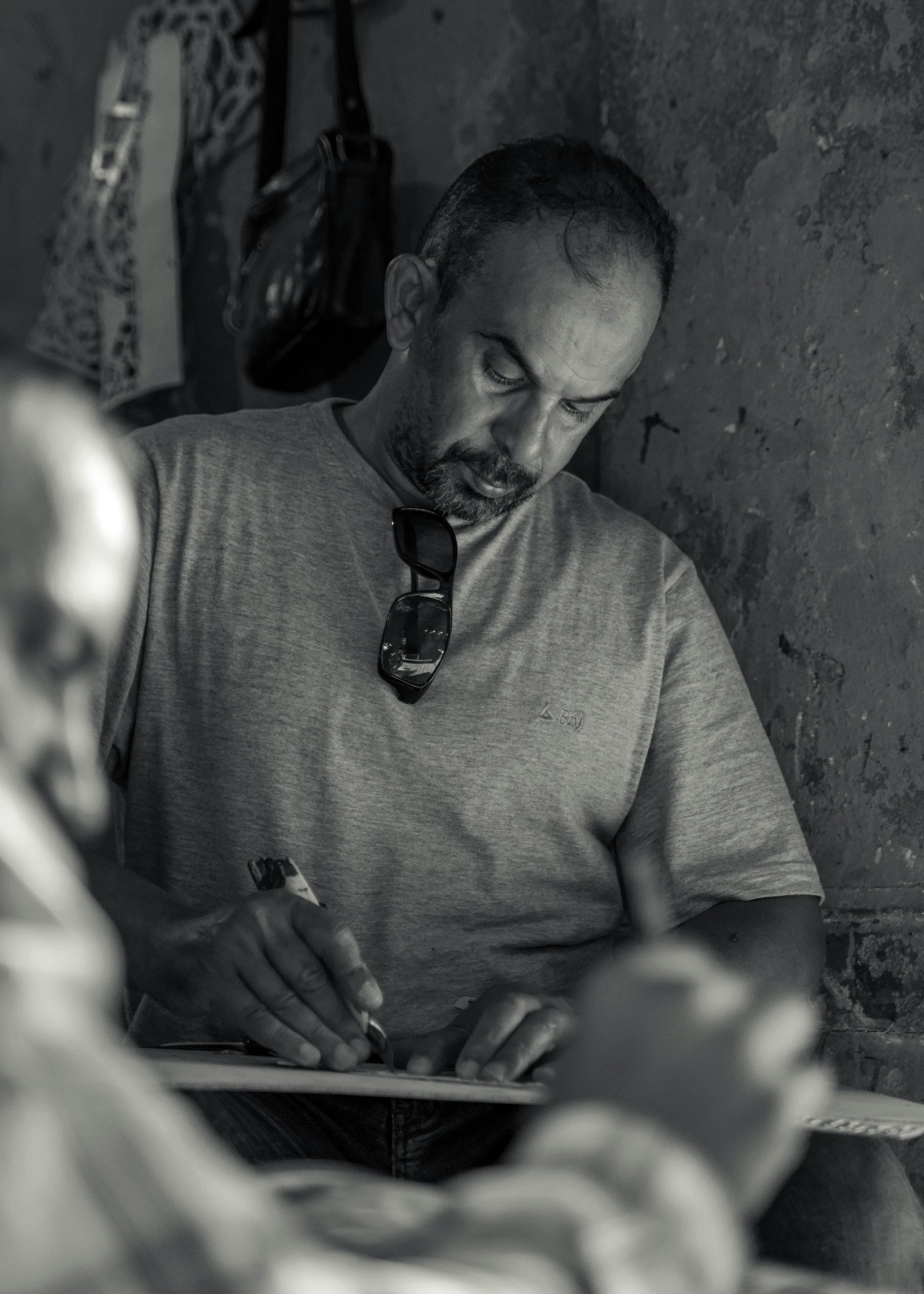 man sitting down writing in his notebook next to another man