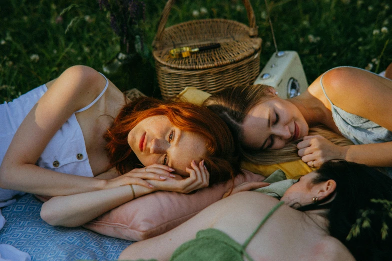 three girls lounging on a blanket outside