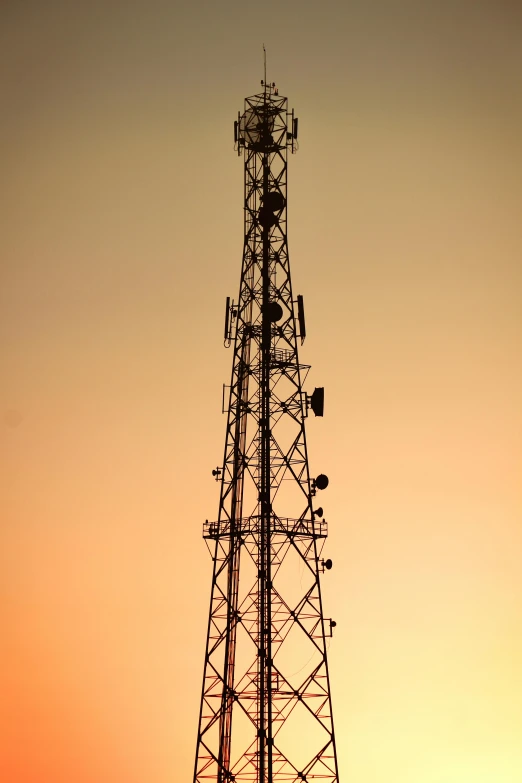 a phone tower with many antennas and some people climbing it