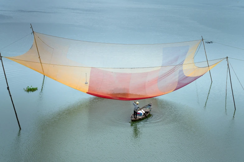 a person in a small boat floats across the water with tarps