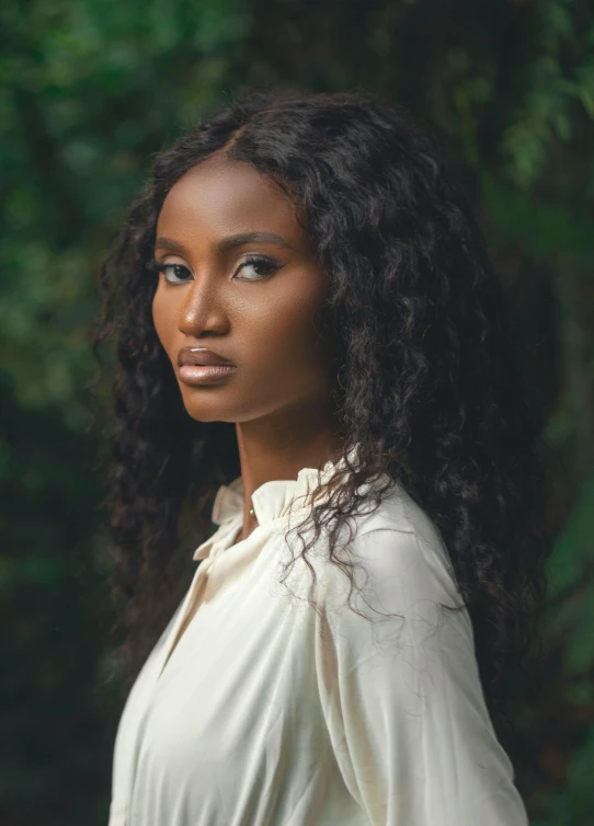 a beautiful woman in a white shirt stands by the woods