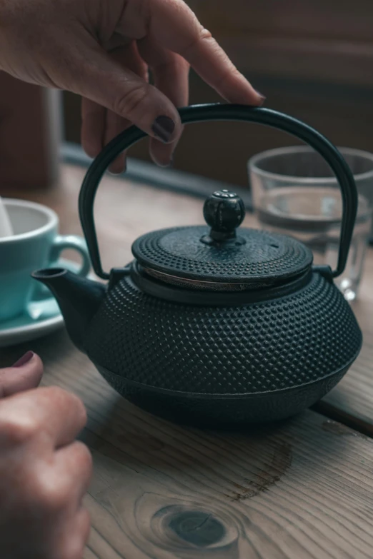 a person that is holding up a tea pot