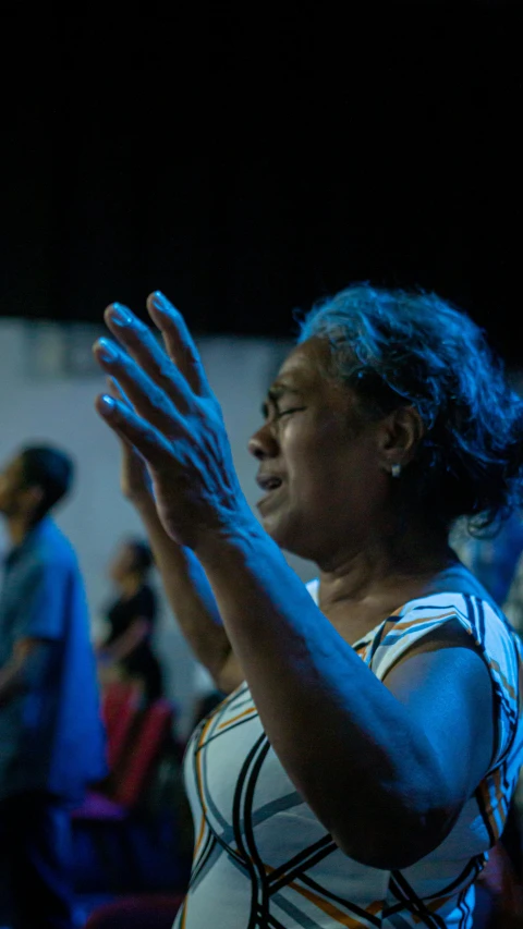 an image of woman clapping in a dark room