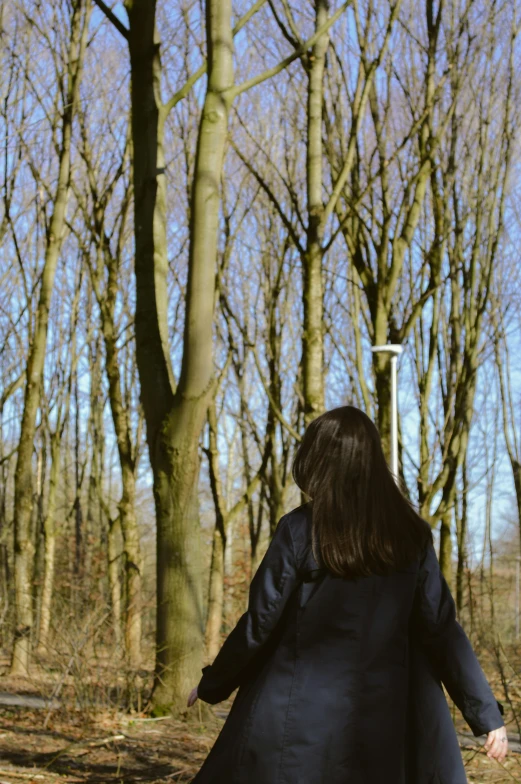 the back view of a woman running towards trees in a park