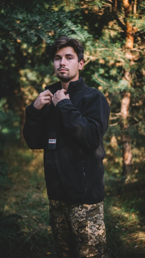 man in camo pants stands near the trees