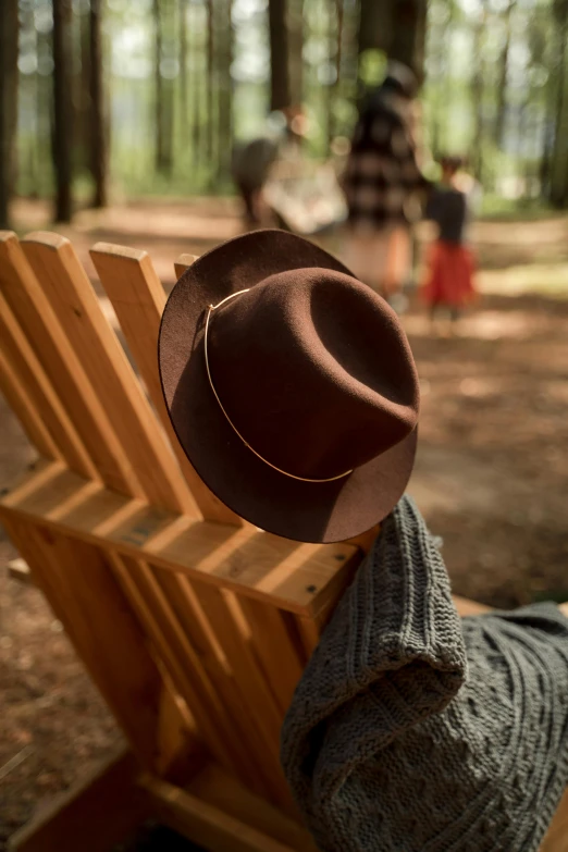 brown hat on a wooden chair with a women sitting down