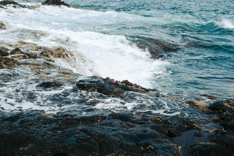 there are people standing on the rocks by the water