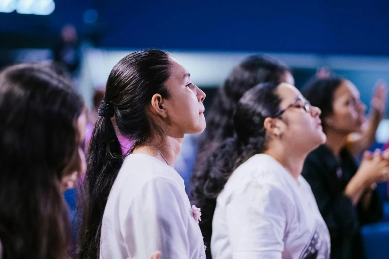 three young women sit at a service in a church