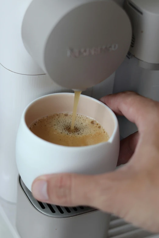 someone pouring coffee from a white cup into their coffee maker