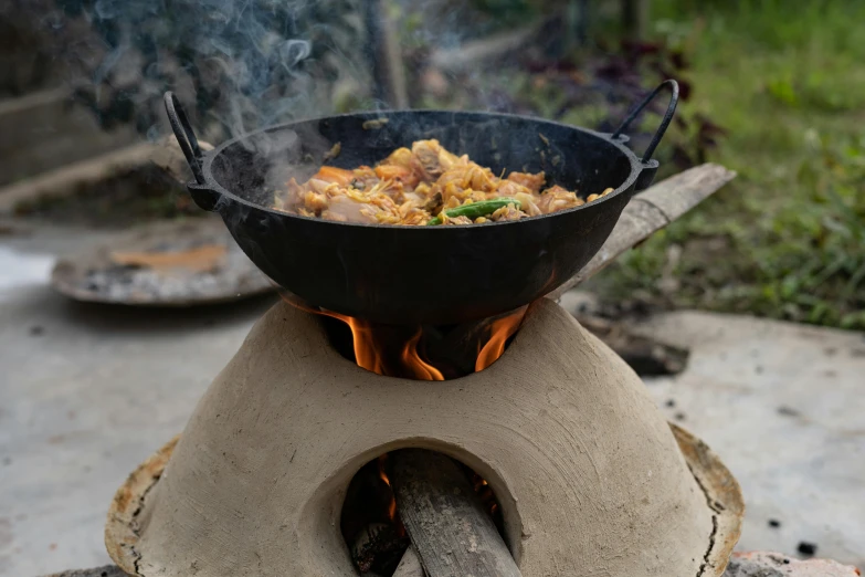 a bowl full of food cooking on top of a fire