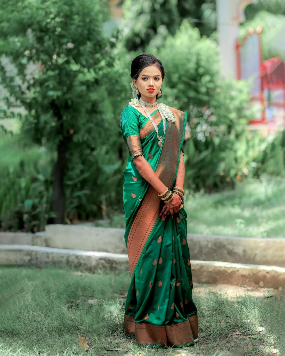 a beautiful young lady dressed in green, tan and brown saree