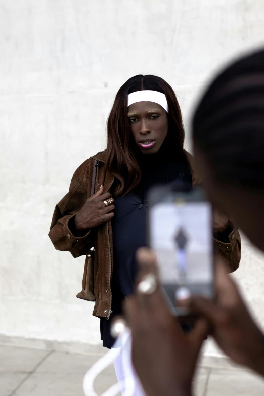 a woman with head covering standing next to a man looking at his phone